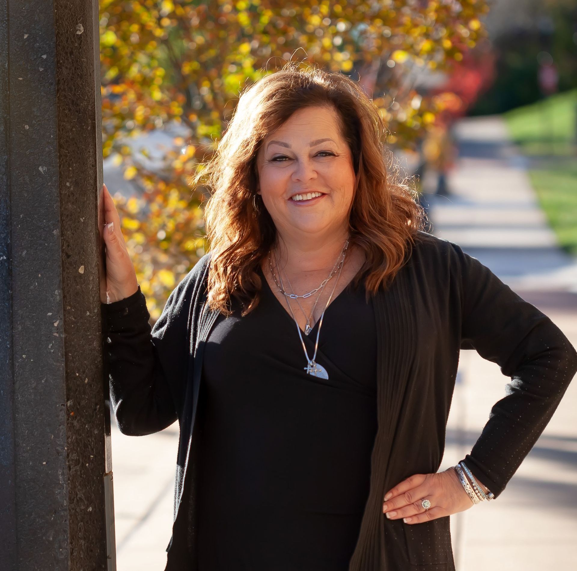 A woman leaning against a pole with her hands on her hips