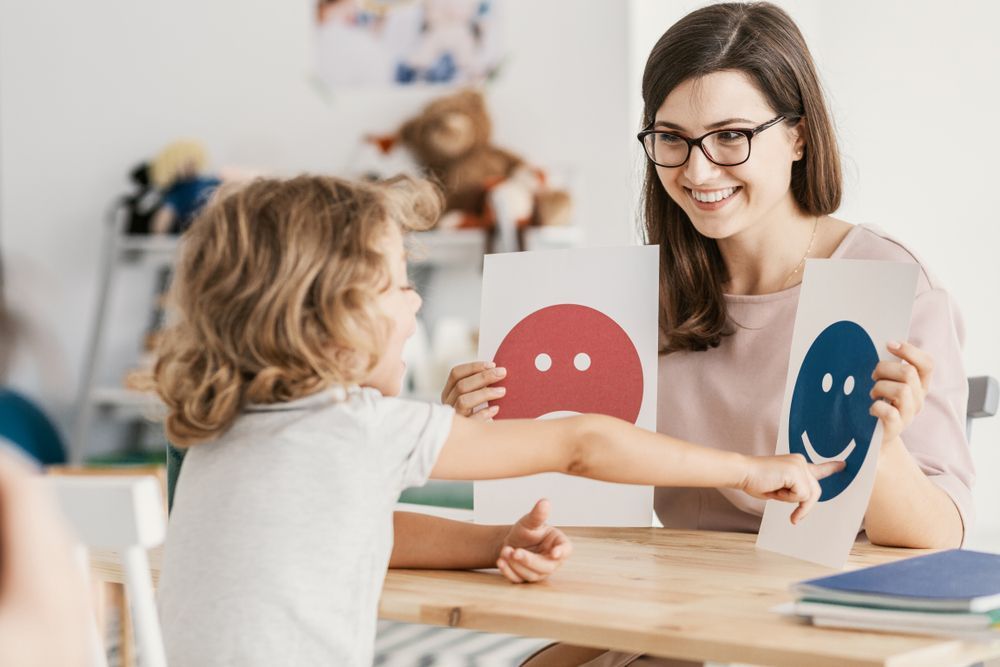 A Child Points to a Card With a Happy Blue Face — Moreton Bay Therapy in Deception Bay, QLD