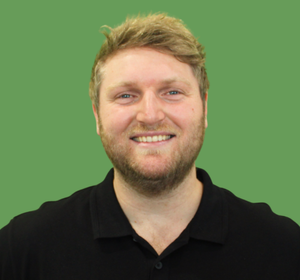 Smiling person in a black polo shirt against a green background — Moreton Bay Therapy in Deception Bay, QLD