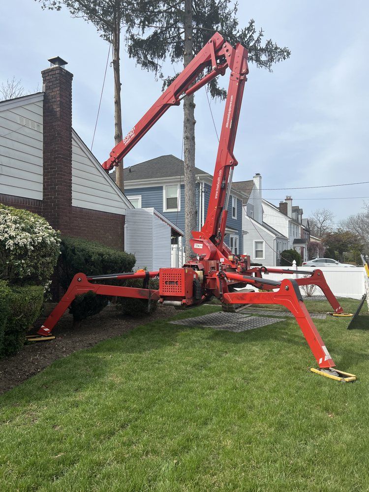A red crane is lifting a tree in front of a house.