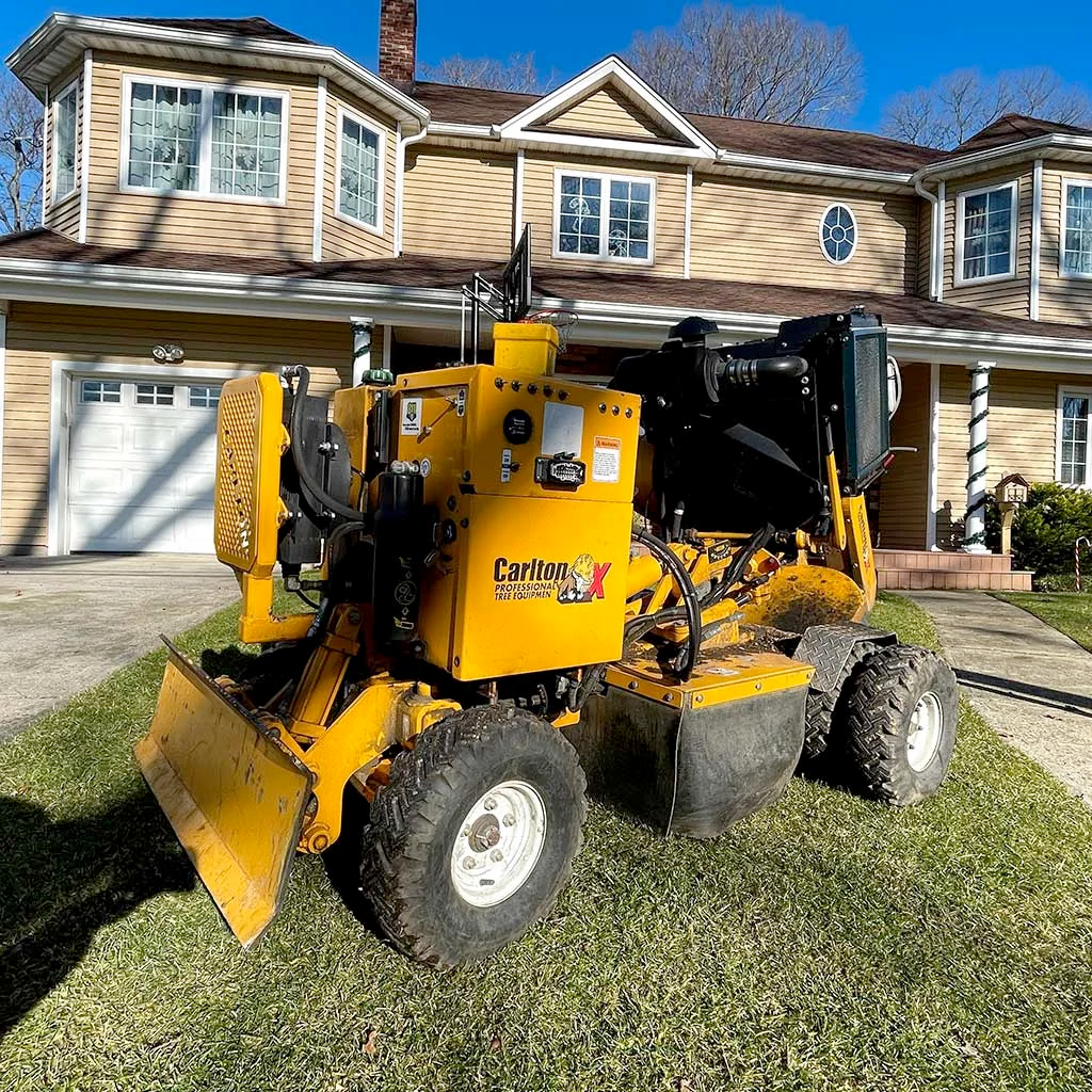 A yellow tractor is parked in front of a house.
