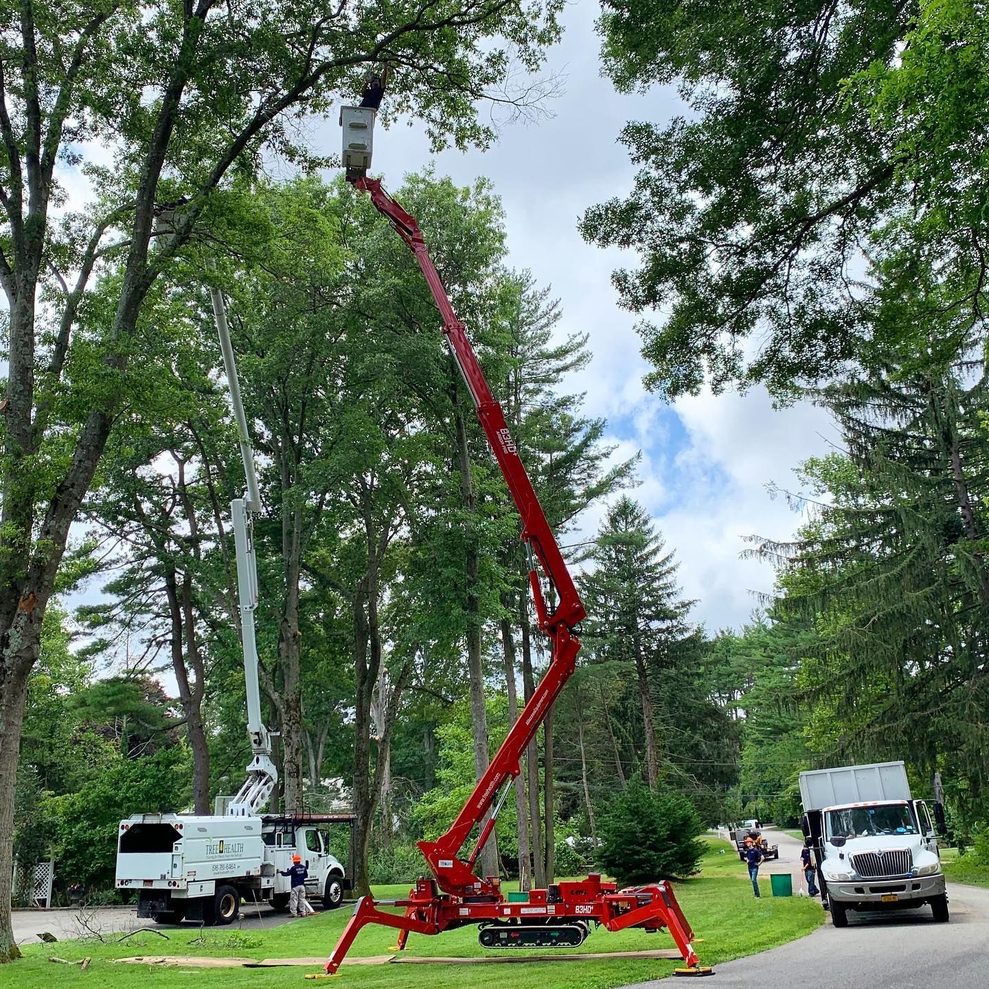 A red crane is sitting on the side of a road next to a truck.