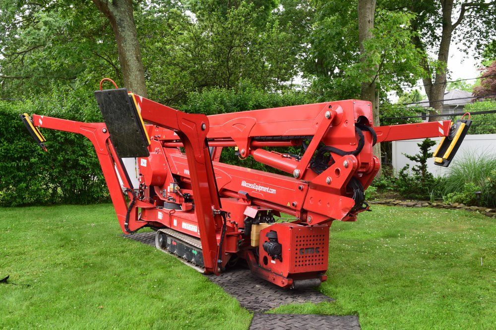 A red crane is sitting on top of a lush green lawn.