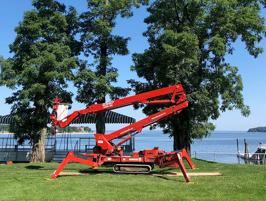 A red crane is sitting on top of a lush green field next to a body of water.