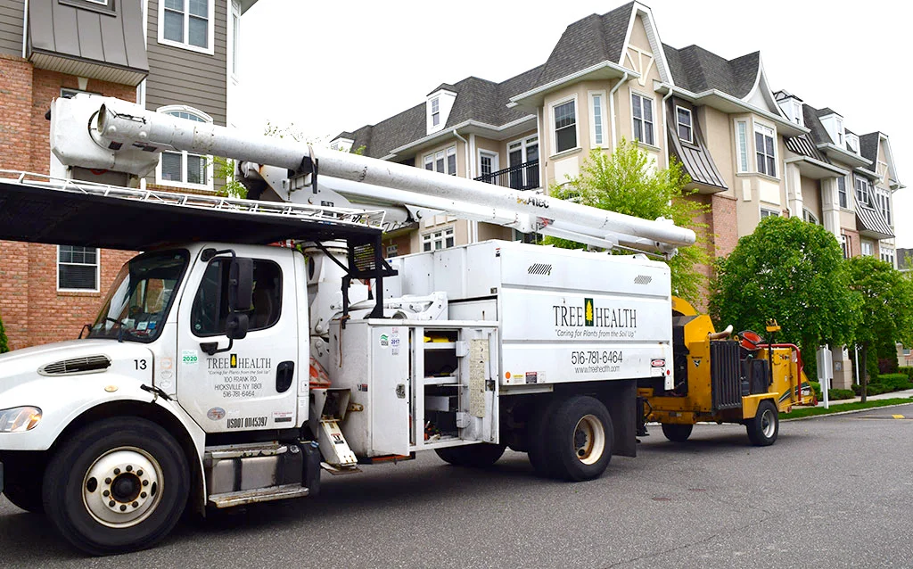 A white truck with a yellow trailer is parked in front of a brick building.
