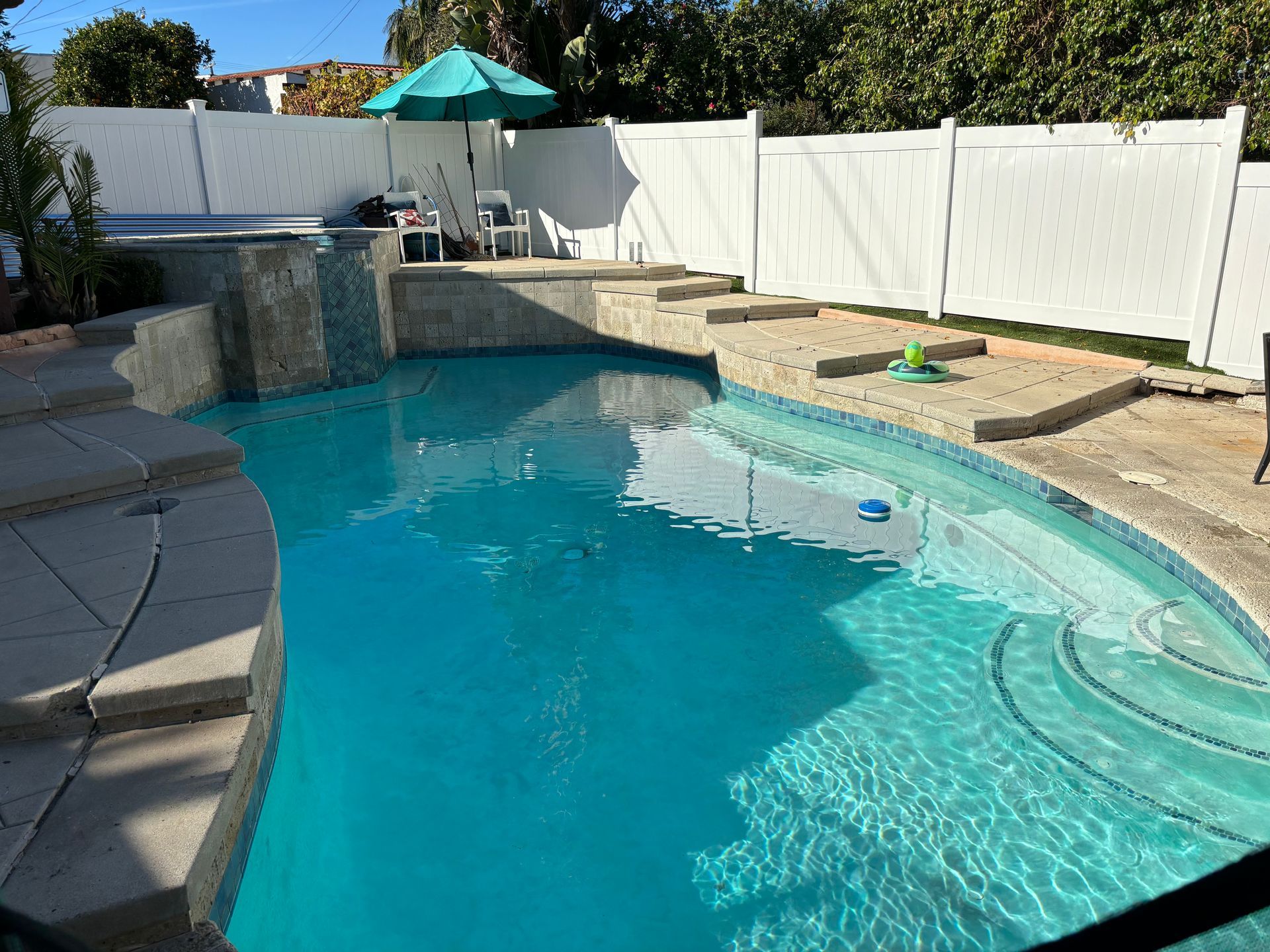 A large swimming pool with a white fence surrounding it.