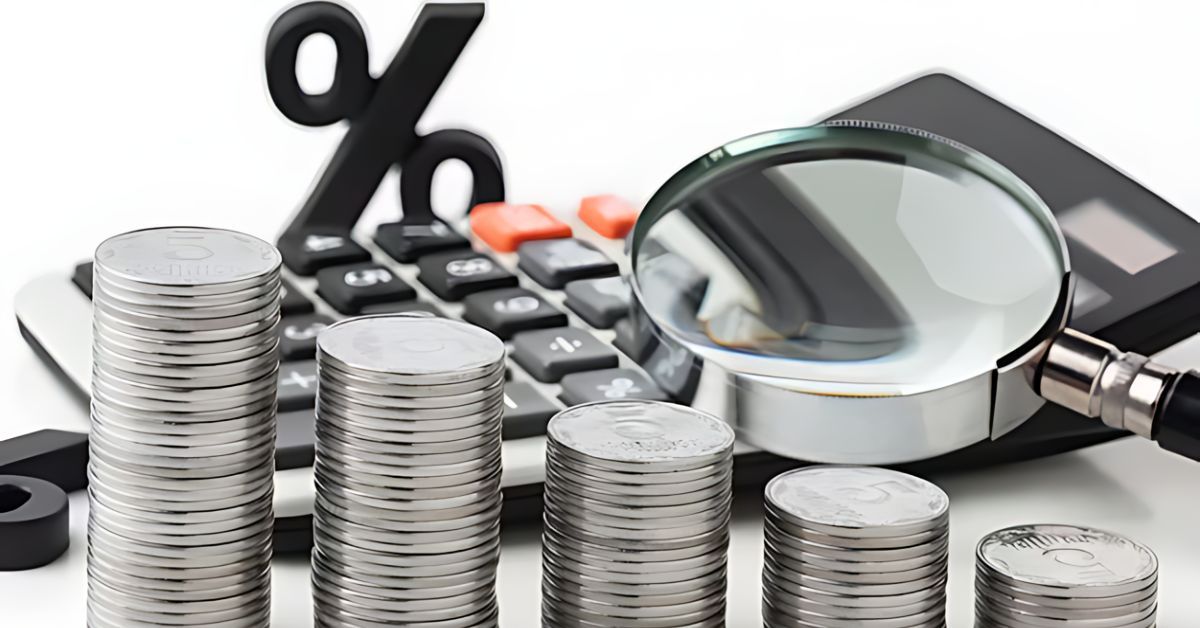 Several silver coin stacks, a magnifying glass, and a calculator.  A percentage sign is in the background.