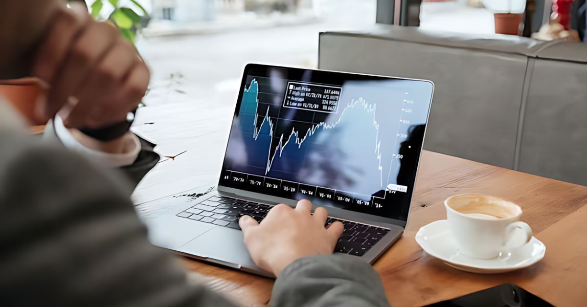 A man using a computer that is showing a monetary growth chart.