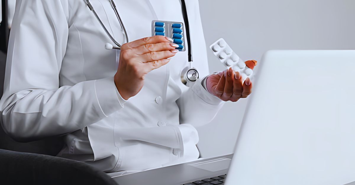 Medical doctor holding two prescriptions while sitting at a desk.