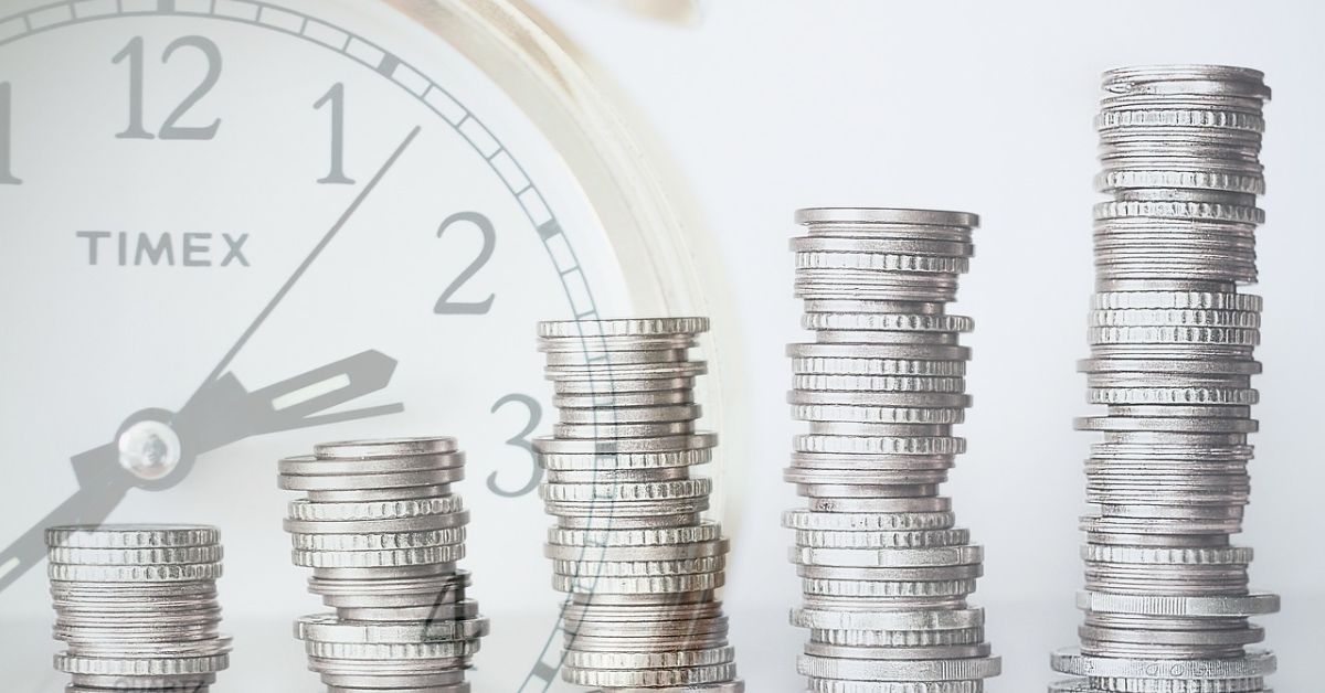 Piles of coins with a Timex watch in the background.