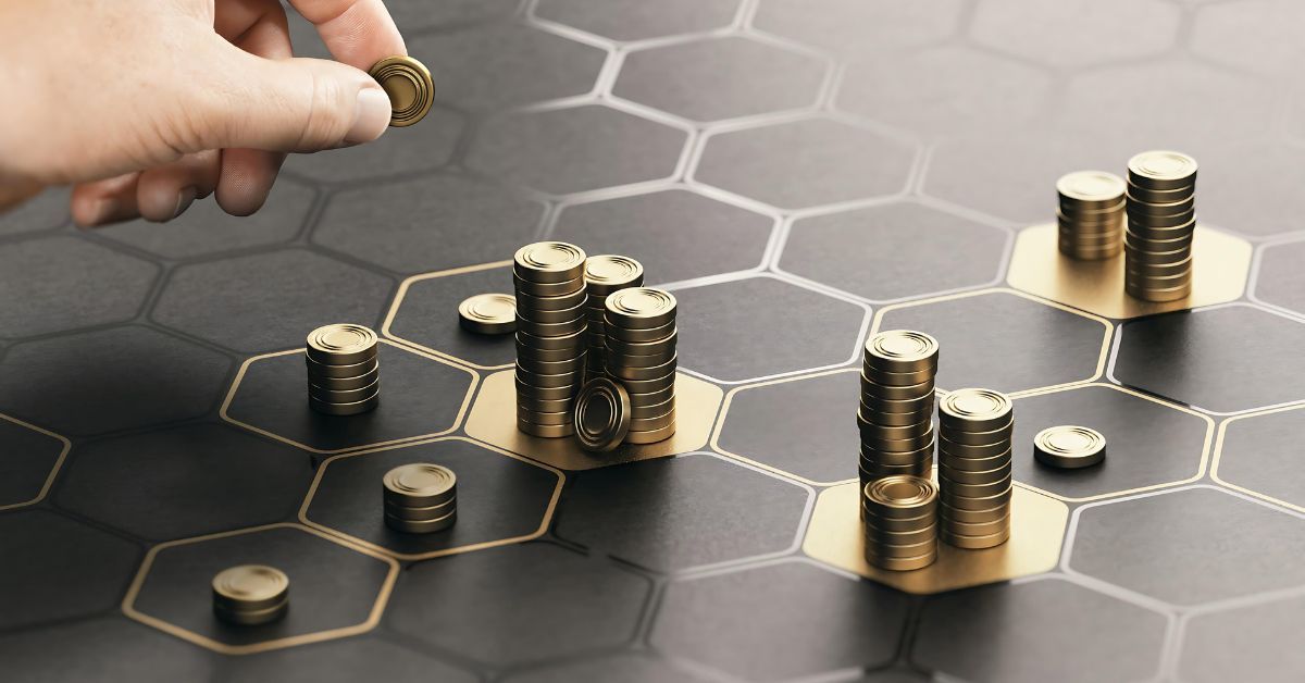 A hand stacking gold coins into piles.