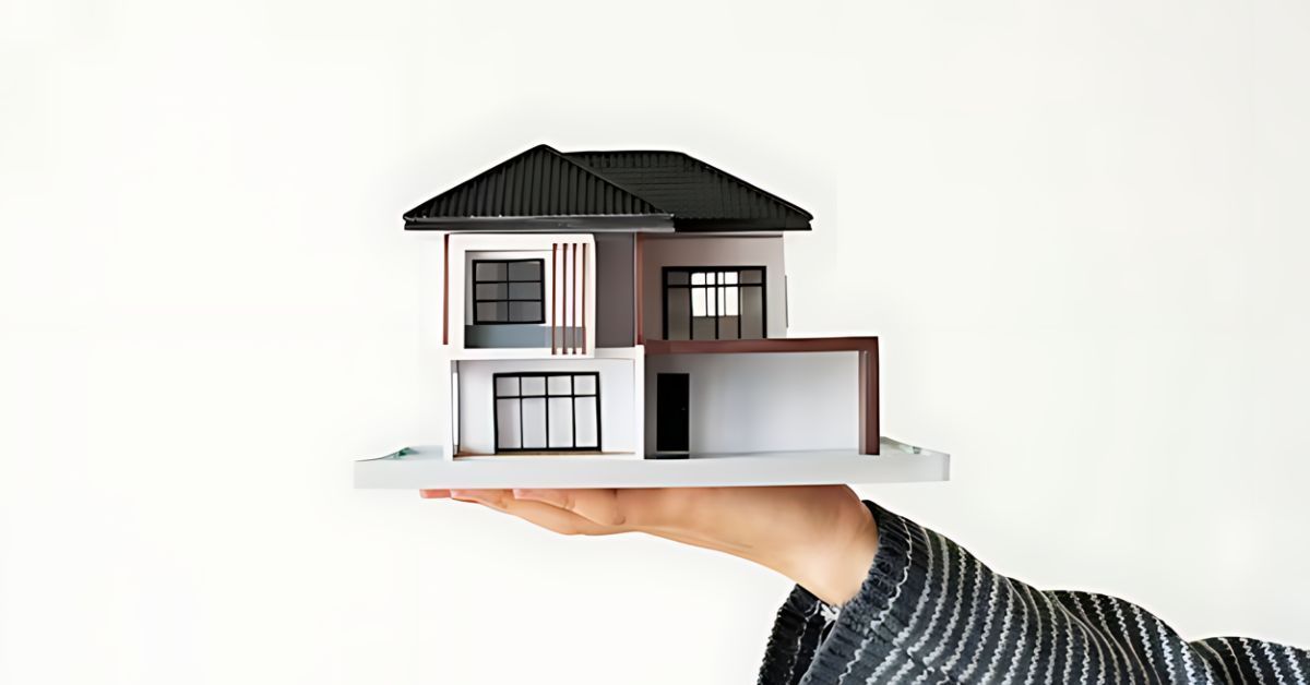 A hand holding a figurine model of a house.