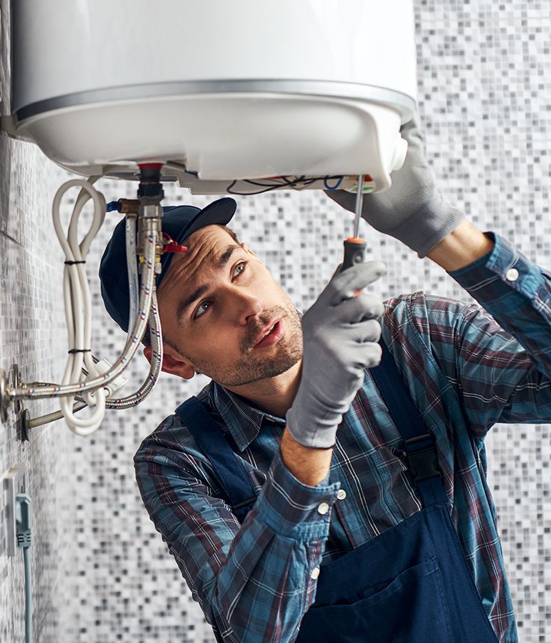 A man is fixing a water heater with a screwdriver.