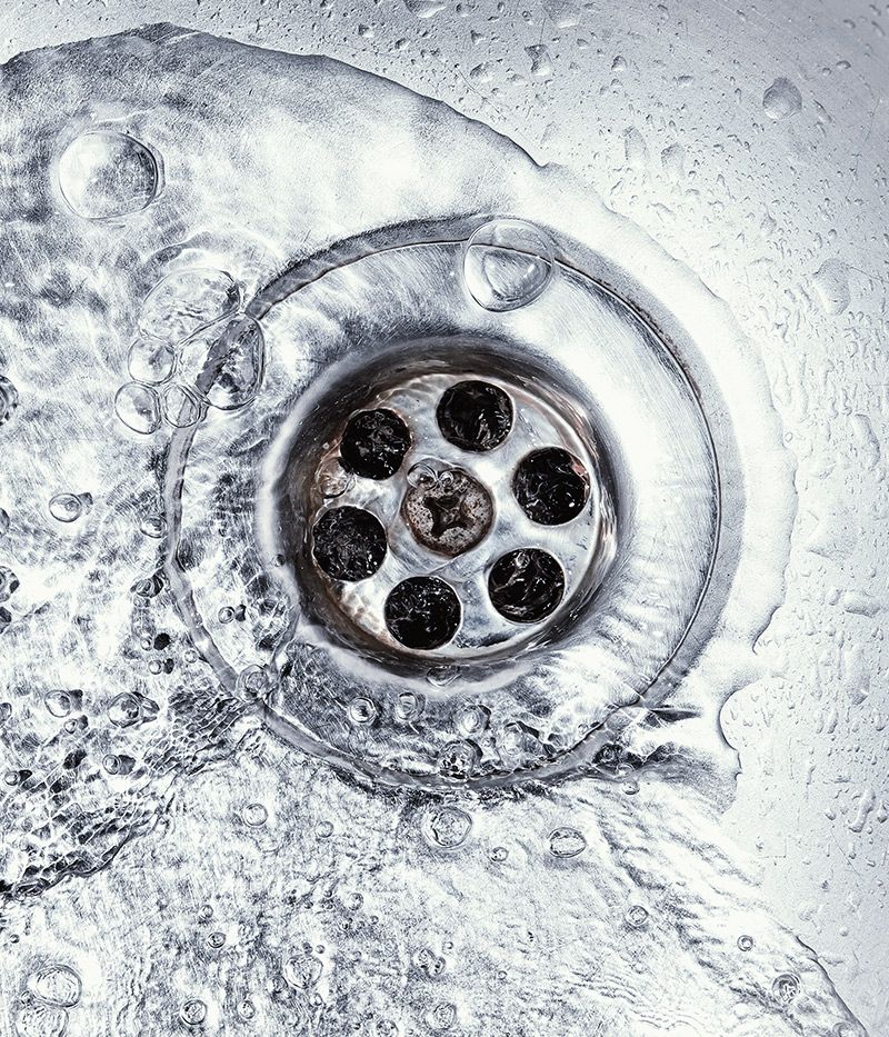 A close up of a sink drain with water running down it