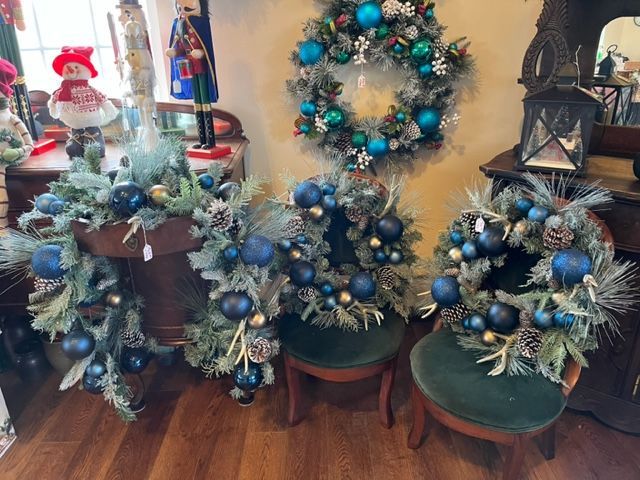 A group of christmas wreaths are sitting on a wooden floor in a room.