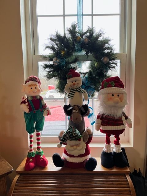 A group of stuffed christmas characters are sitting on a table in front of a window.