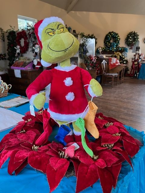 A stuffed grinch is sitting on top of a poinsettia flower.