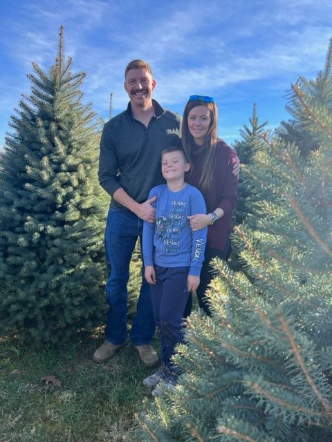 A family is posing for a picture in front of a christmas tree.