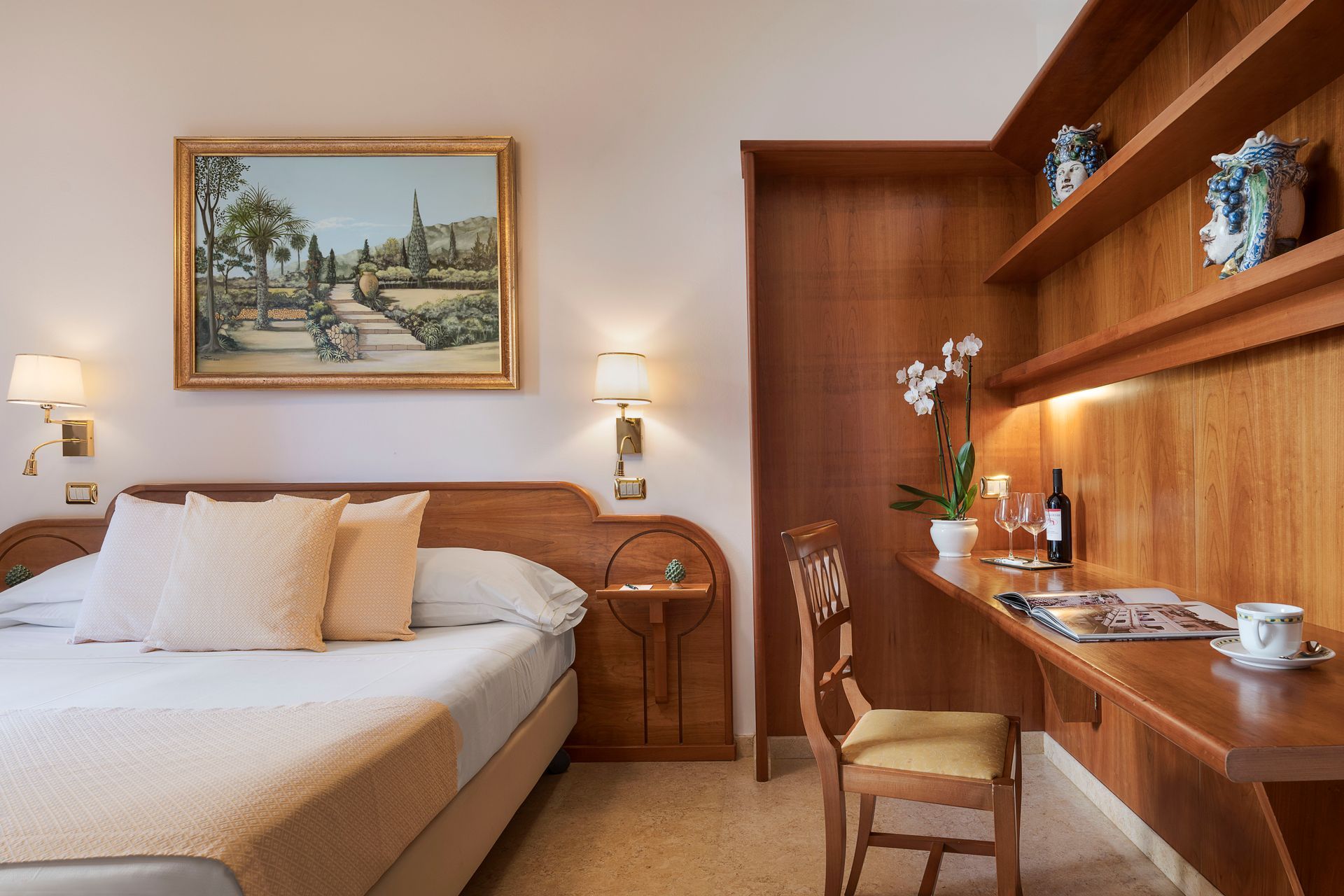 Chambre chaleureuse avec lit blanc, bureau en bois et tableau de paysage encadré au mur.