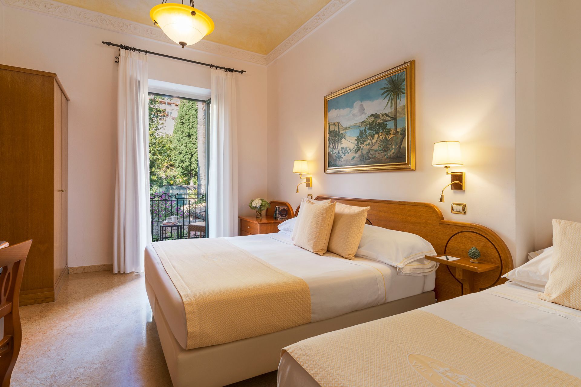 Chambre d'hôtel lumineuse avec deux lits jumeaux, murs couleur crème et porte-fenêtre