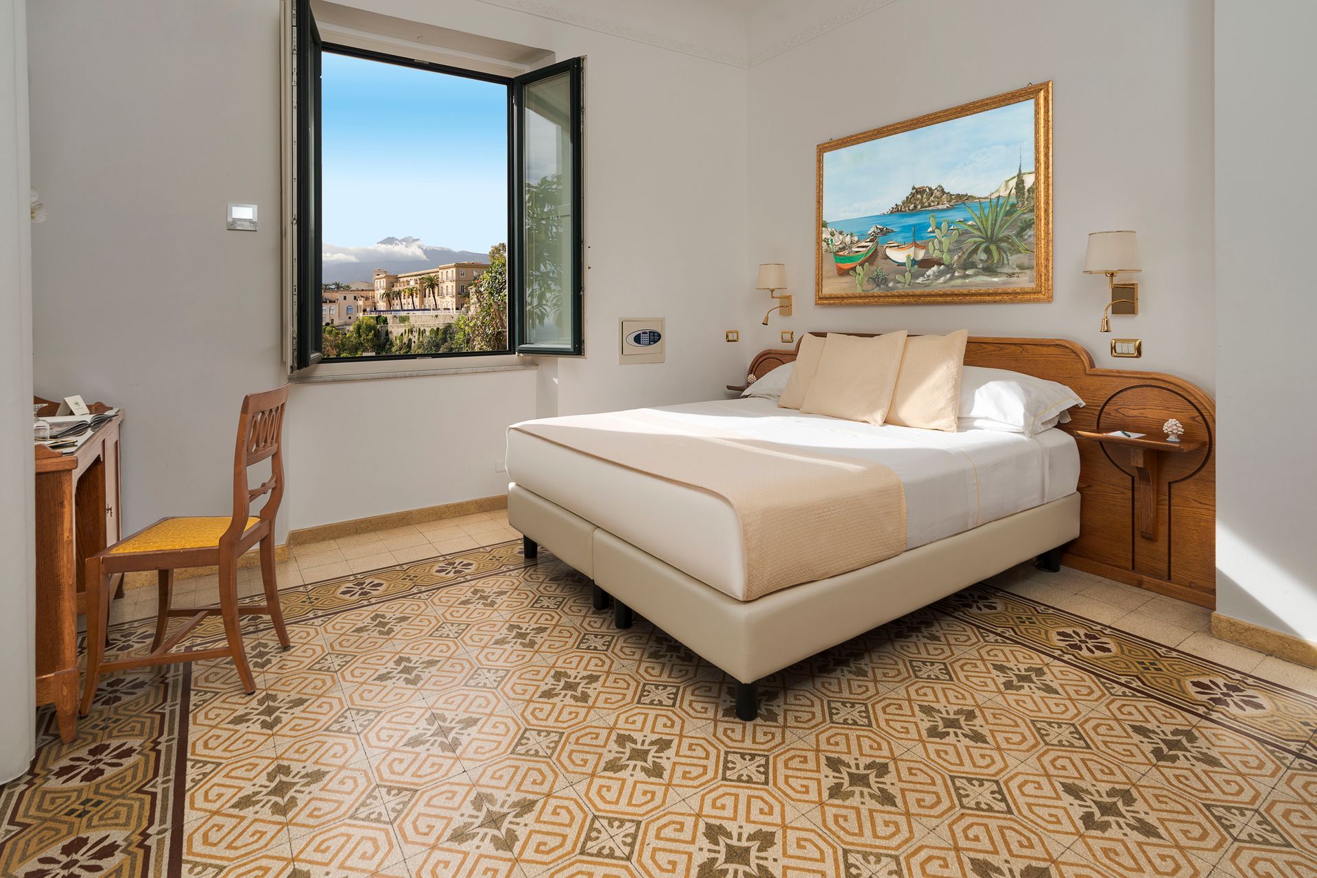Bright bedroom with a double bed, open window, patterned tile floor, and seaside view.