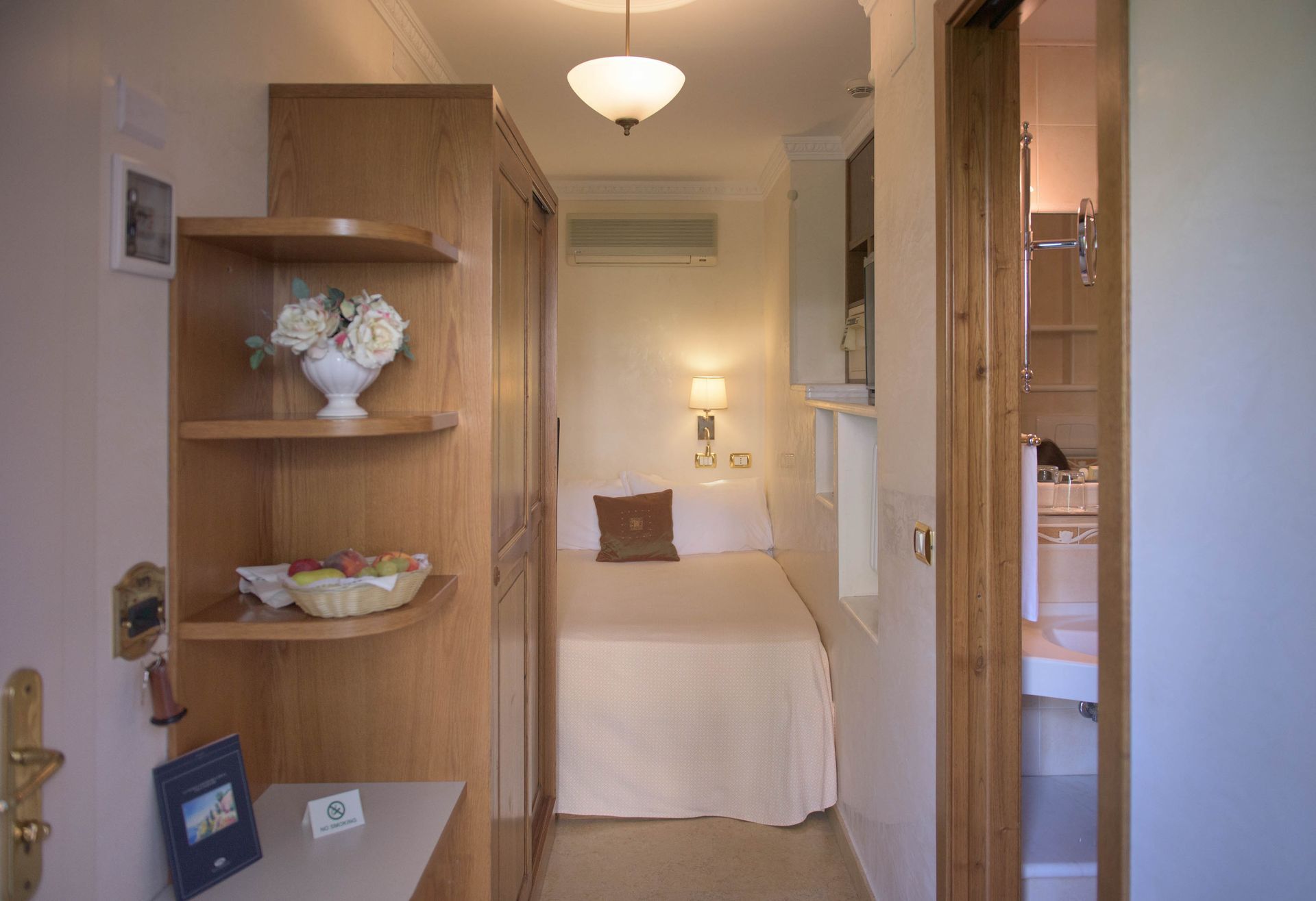 Cozy bedroom with wood shelves, a neatly made bed, and a doorway to the adjoining room.
