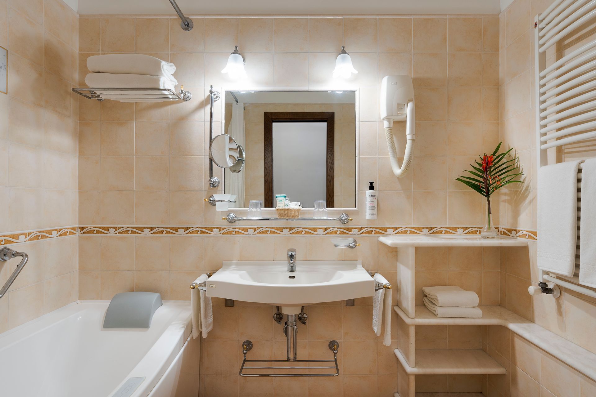 Beige-tiled bathroom with bathtub, pedestal sink, mirror, and window blinds
