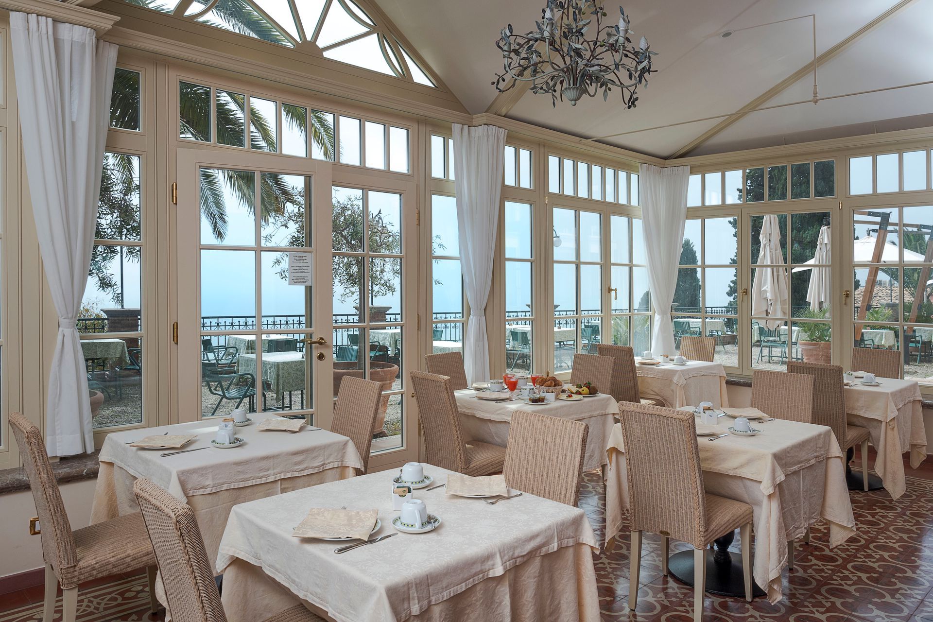 Elegant seaside dining room with set tables, large windows, and ocean views