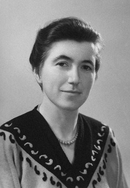 Portrait of a woman in a patterned dark top, facing the camera with a slight smile