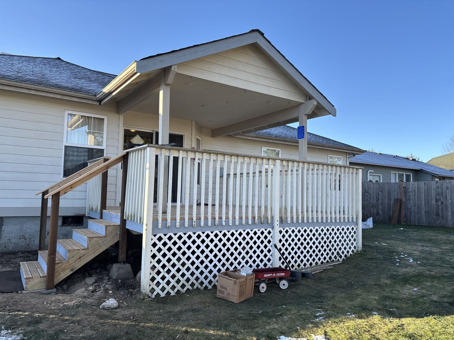 A house with a porch and stairs and a red wagon in front of it.