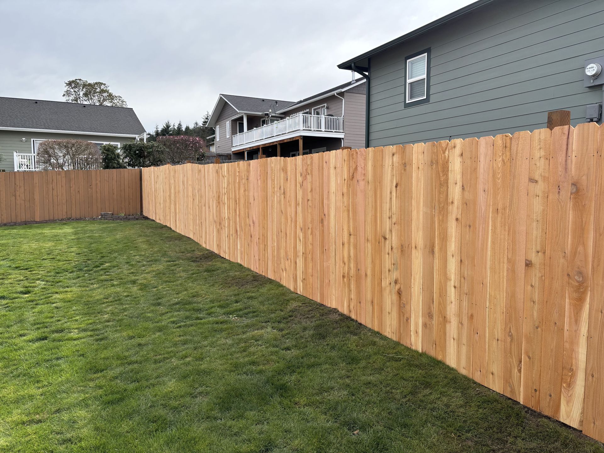 A wooden fence is in the backyard of a house.