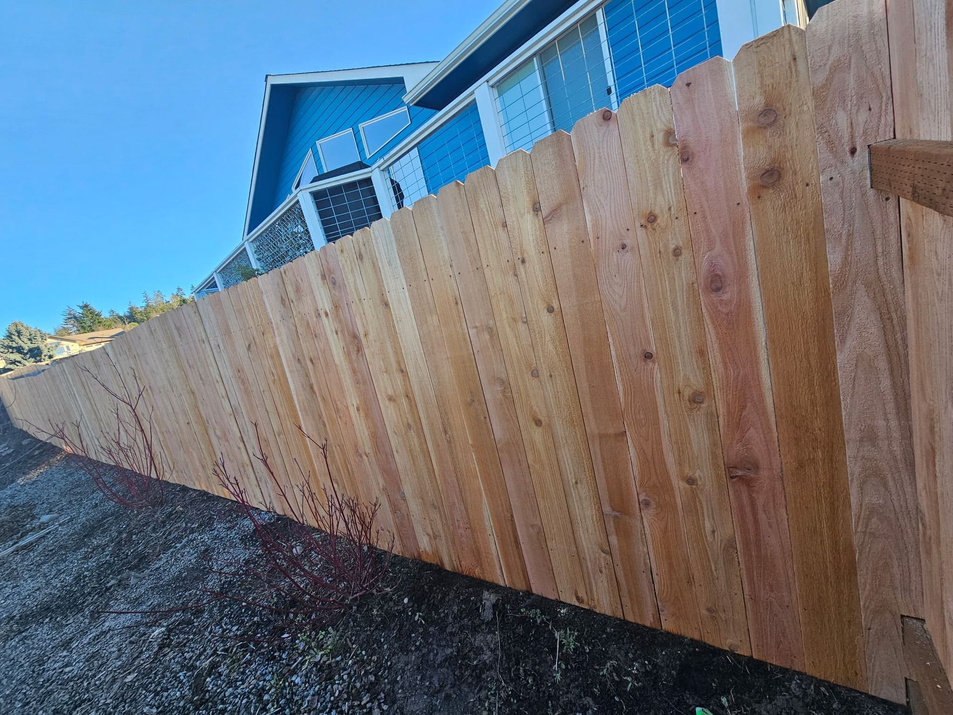 A wooden fence is sitting in front of a blue house.