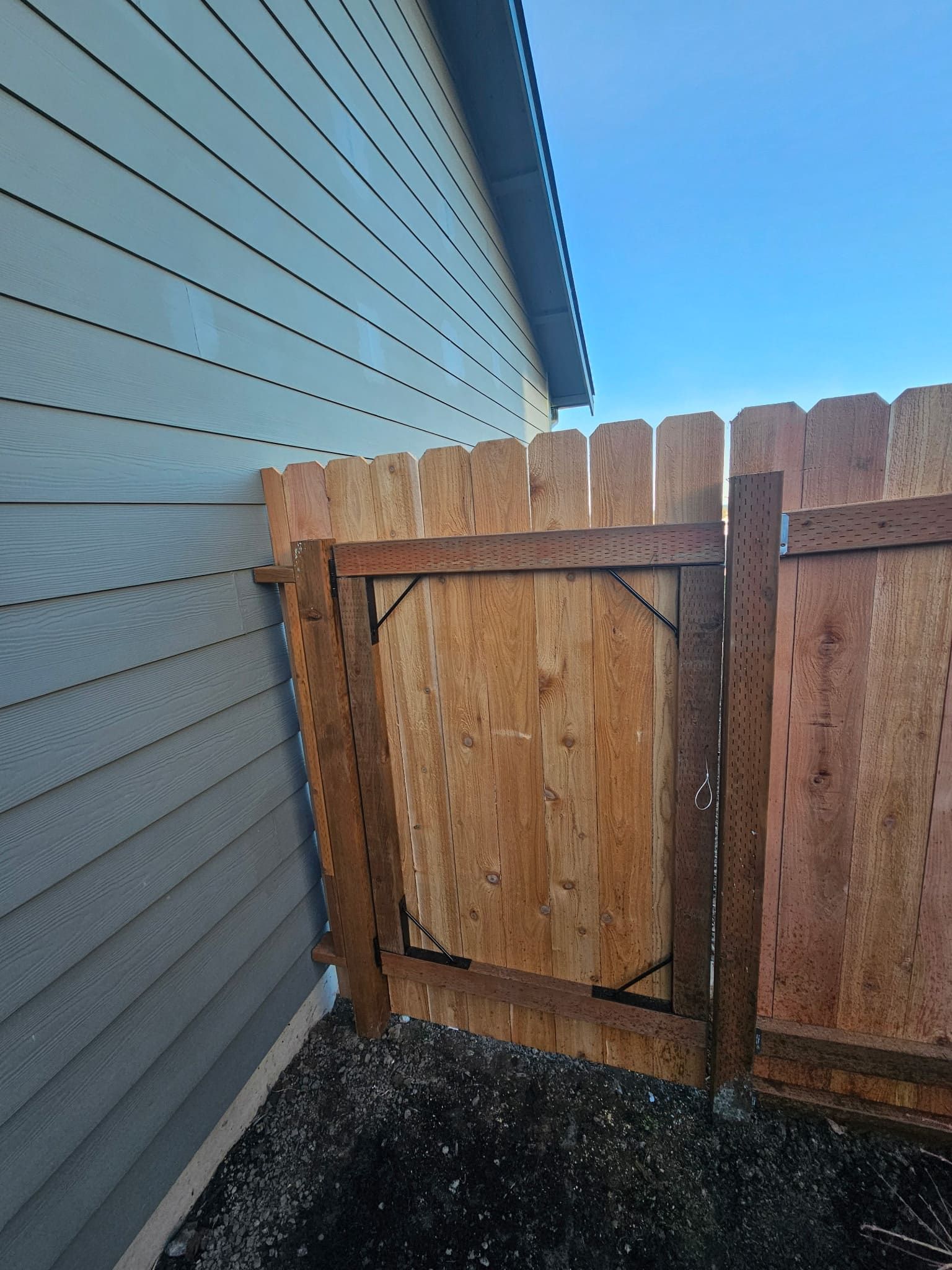 A wooden fence with a gate is next to a house.