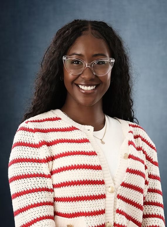 Woman with glasses wearing a striped cardigan, smiling at the camera.