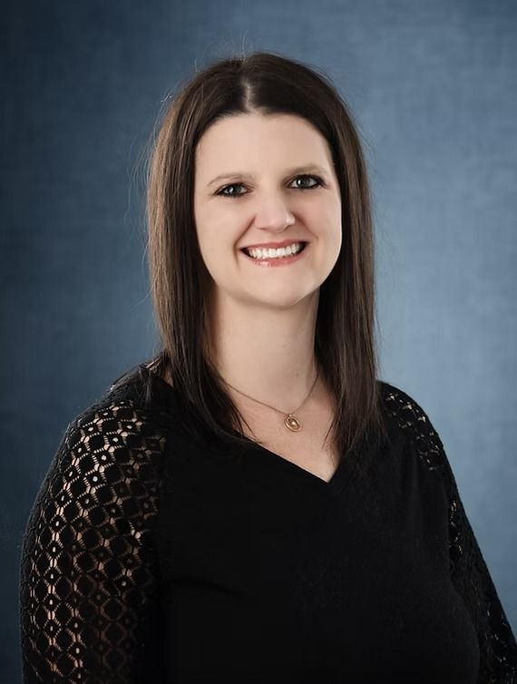 Woman smiling, wearing a black top, against a blue background.