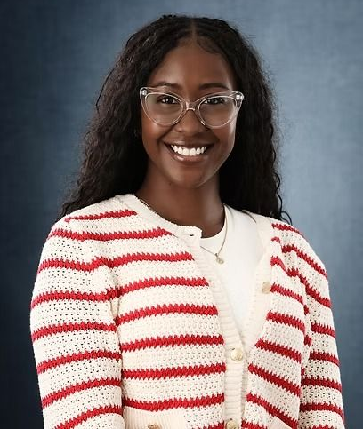 Woman with glasses smiles, wearing striped red and white sweater.