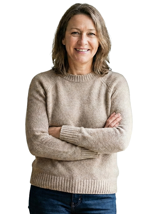 Woman in tan sweater, arms crossed, smiling, posing against a white backdrop.
