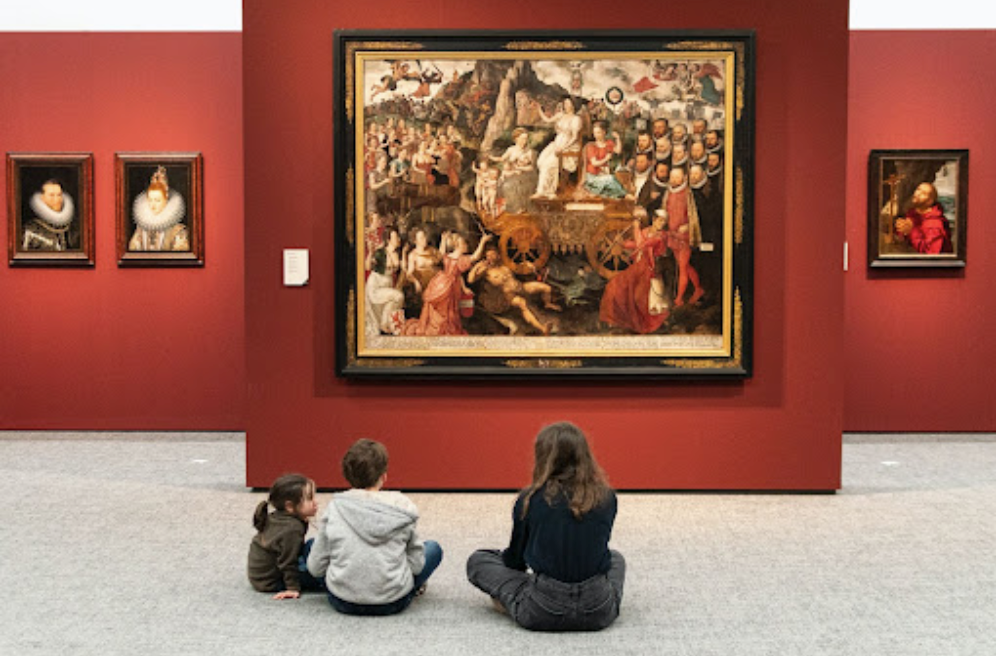 Woman with glasses smiles, arms crossed, wearing a black top against a blue background.