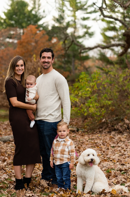 Woman smiling, wearing a white and red floral top, with shoulder-length brown hair, against a blue background.
