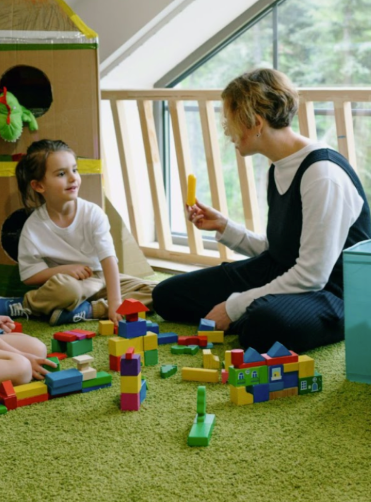 Woman with dark hair, smiling, wearing a light blue cardigan, against a blue background.