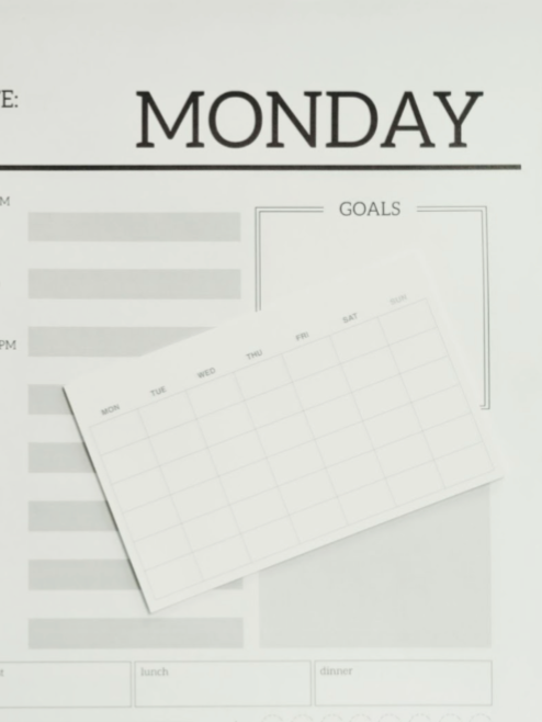 Woman with glasses smiles, arms crossed, wearing a black top against a blue background.