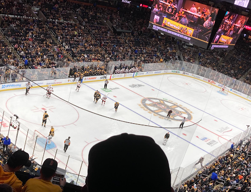 Man with dark hair and stubble in a denim shirt, looking directly at the camera against a blue backdrop.