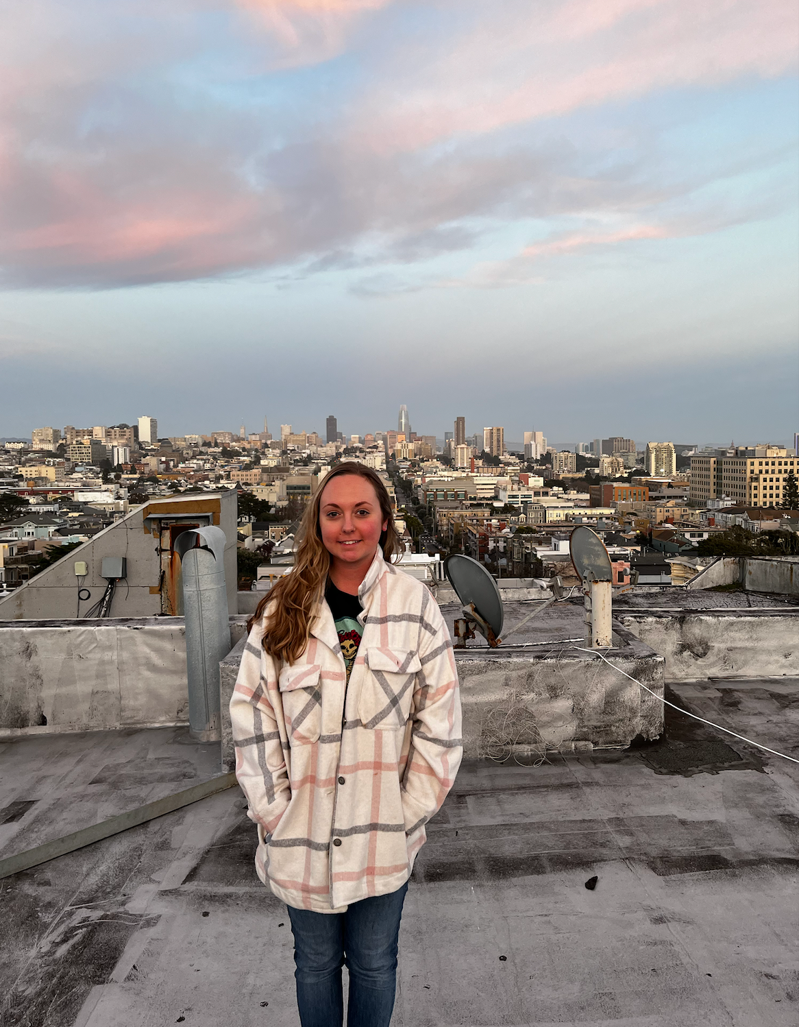 Woman with glasses smiles, arms crossed, wearing a black top against a blue background.