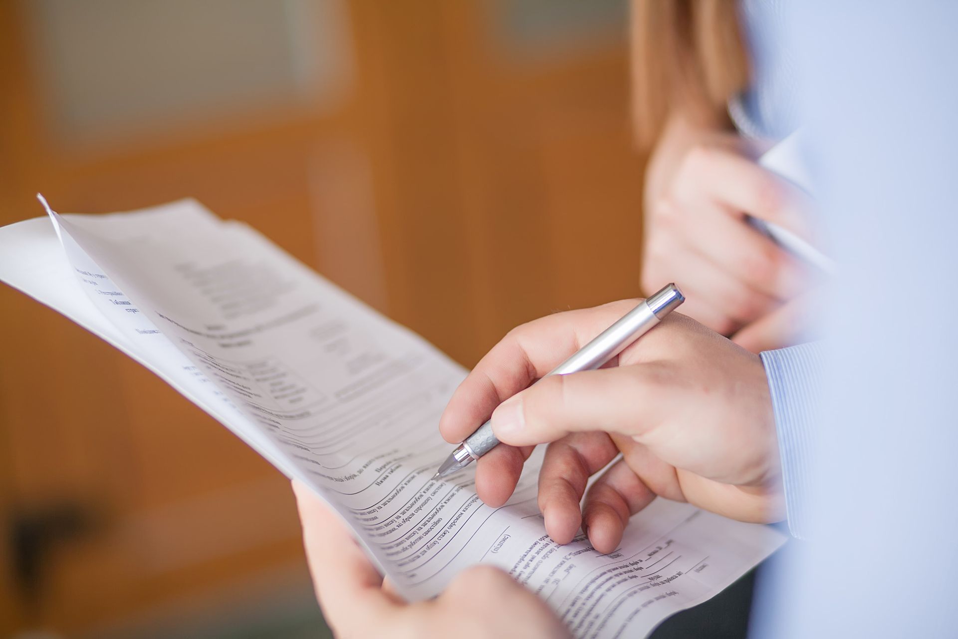 Person holding a pen, reviewing and marking a document.