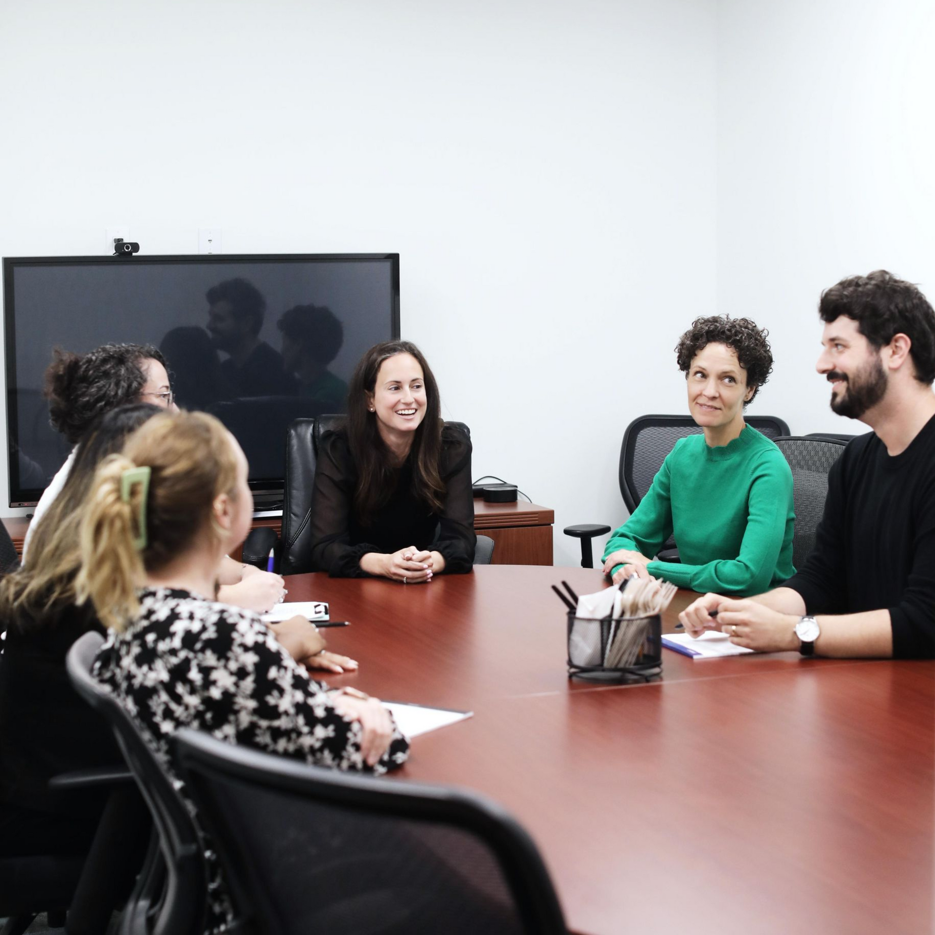 People seated around a conference table in an office, engaged in a discussion.