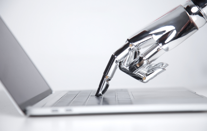 Mano robotica argentata che preme un tasto sulla tastiera di un computer portatile, sfondo bianco.