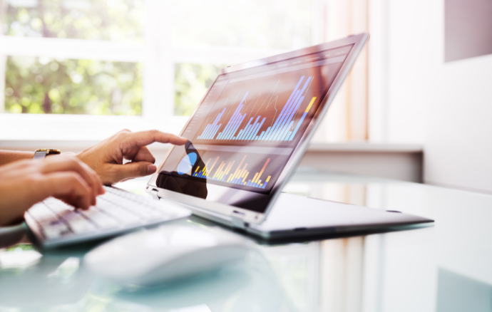 Persona che utilizza un computer portatile con grafici, indicando lo schermo mentre digita sulla tastiera
