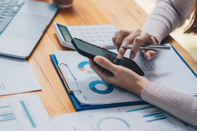 Persona che utilizza uno smartphone, una calcolatrice e un computer portatile.