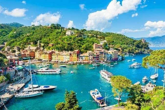 Città costiera di Portofino, in Italia, con edifici colorati che circondano un porto con barche e verdi colline