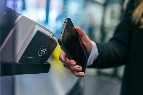 Persona che utilizza il proprio telefono per effettuare un pagamento contactless presso un terminale.